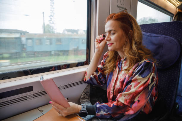 istock Beautiful woman riding train by day, putting make-up on, using smart phone as a mirror 2187286108