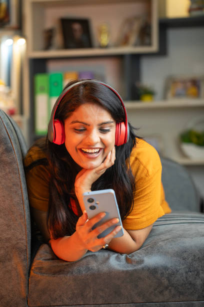 istock Happy young woman using smart phone on sofa at home 2187286361