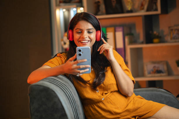 istock Happy young woman using smart phone on sofa at home 2187286412