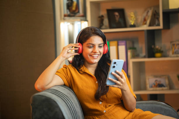 istock Happy young woman using smart phone on sofa at home 2187286424