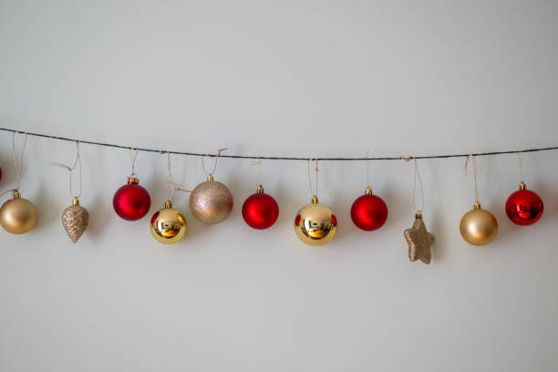 istock Festive Christmas decorations hanging on a string along a wall, featuring red, gold, and glittery ornaments. Perfect for holiday themes. 2187286860