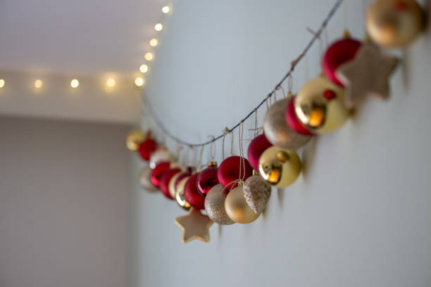 istock Festive Christmas decorations hanging on a string along a wall, featuring red, gold, and glittery ornaments. Perfect for holiday themes. 2187286867