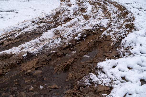 Tire tracks in the ice mud of winter in rural with snow. Off-road in frozen land. Landscape nature background.