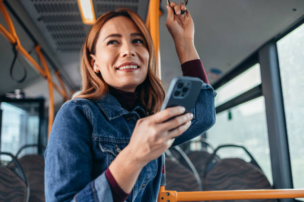 istock Cheerful woman using smartphone and earbuds on bus during commute 2187291057
