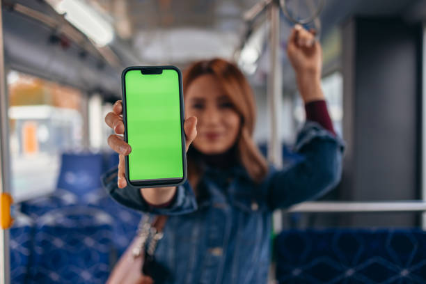 istock Young woman showing green screen smartphone on bus 2187291359