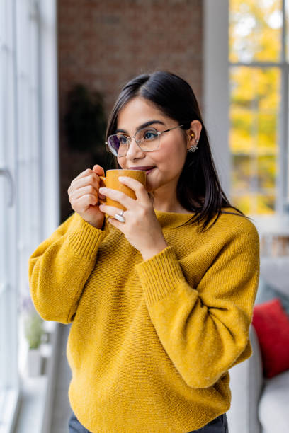 istock A woman savoring coffee while gazing outside window. 2187293302