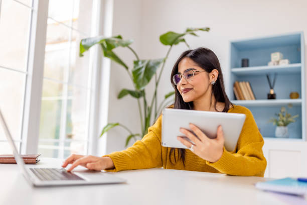 istock Bright office with woman using a tablet and laptop 2187293406