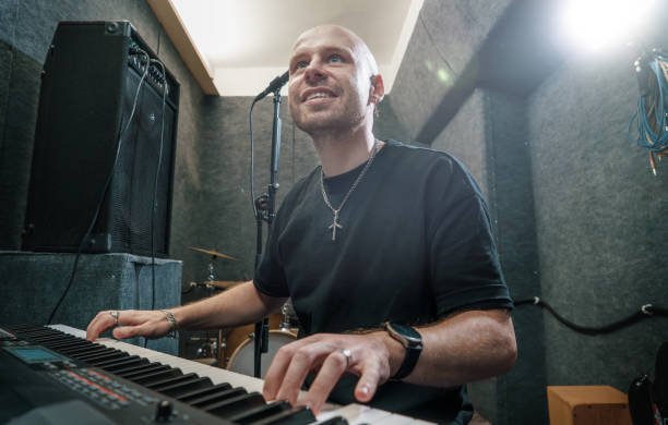 istock Musician playing keyboard in recording studio, smiling and enjoying creative process. Professional music equipment in background, inspiring and dynamic atmosphere for creativity 2187293724