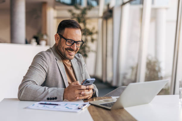 istock A confident businessman is using a mobile phone in a modern office 2187293817