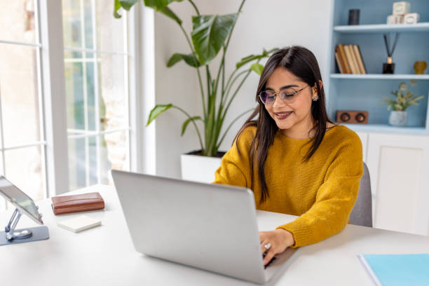 istock Focused woman typing on laptop in bright office space 2187299147