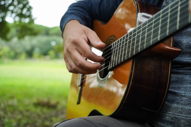 Man Playing Guitar Outdoor in Green Park on Summer Day