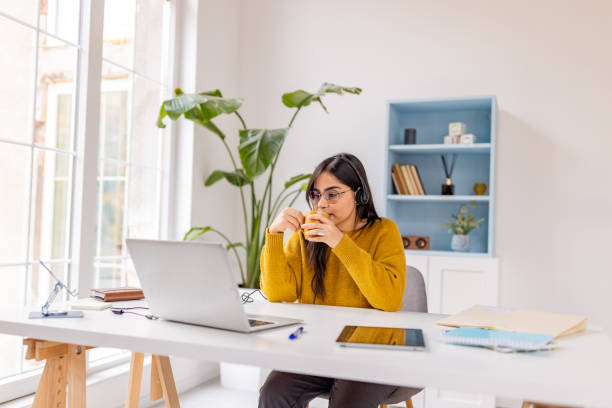 istock Focused woman with coffee at laptop, cozy workspace. 2187299594
