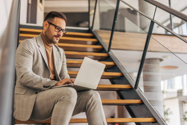 istock A businessman is using a laptop while sitting on indoor stairs 2187299757