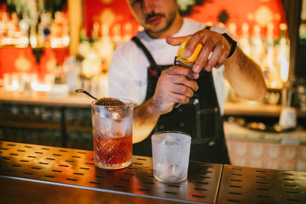 istock Male bartender preparing Negroni cocktail with an orange zest. 2187299836