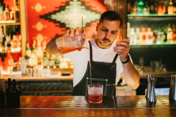 istock Male bartender preparing Negroni cocktail with an orange zest. 2187299852