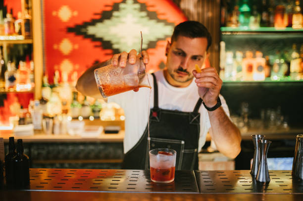 istock Male bartender preparing Negroni cocktail with an orange zest. 2187299853