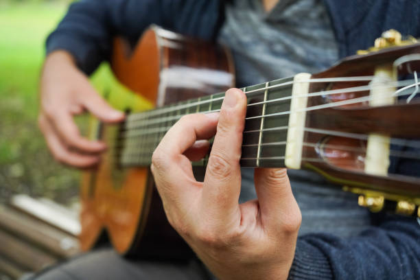 istock Man Wearing Sweater Playing Guitar in Green Park 2187299931