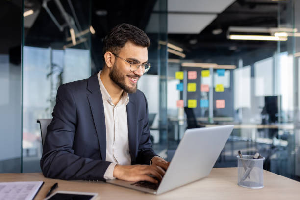 istock Smiling businessman using laptop in modern office 2187299964