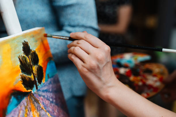 istock Artist painting a colorful landscape with a tree in a creative workshop 2187300429