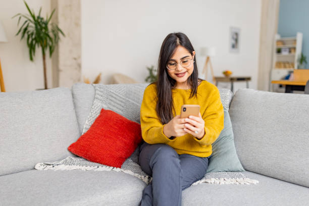 istock Smiling woman engages with phone in cozy home setting 2187301910