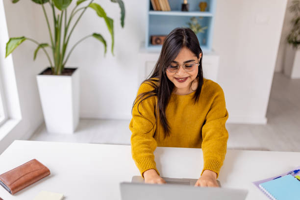 istock Smiling woman typing on laptop at bright desk 2187302246