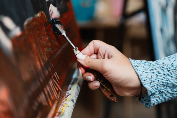 istock Artist applying black paint to canvas in brightly lit studio during daytime 2187302446