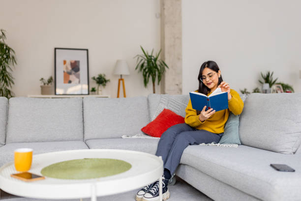 istock Woman reading on a large sofa in a bright living room 2187305568