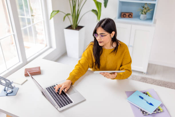 istock Woman working with laptop and tablet at white desk 2187306649
