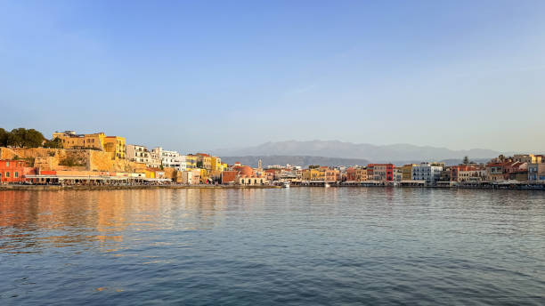Chios port town reflecting on calm water during golden hour, with mountains in background