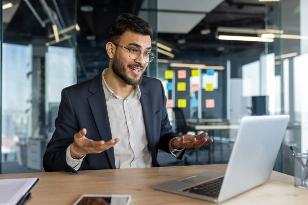 istock Confident businessman engaging in a virtual meeting from modern office, emphasizing communication, professionalism, and connection. Laptop and smartphone on desk suggest digital workspace. 2187308317