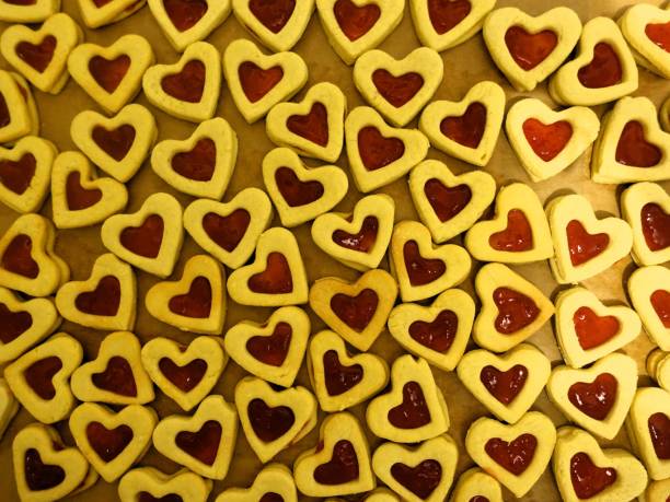 A heart-shaped waffle rests on a clean white surface, showcasing its golden-brown color and unique texture. This delightful treat is perfect for sharing at any occasion.