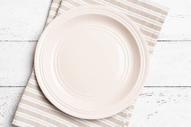 istock Empty plate and linen napkin on white wooden table 2187309375