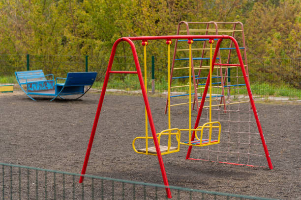 istock Brightly colored swings stand in an empty playground, surrounded by lush greenery. This inviting setting encourages children to engage in active play and create joyful memories outdoors 2187312946