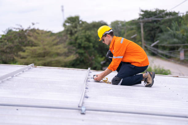 istock Focused worker in an orange safety uniform helmet kneeling on a rooftop holding tools. A scene showcasing attention to detail, safety, and commitment to electrical or structural installation tasks. 2187314043