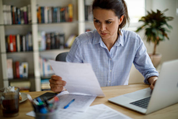 istock Woman reviewing her tax documents while working at her desk at home 2187314501