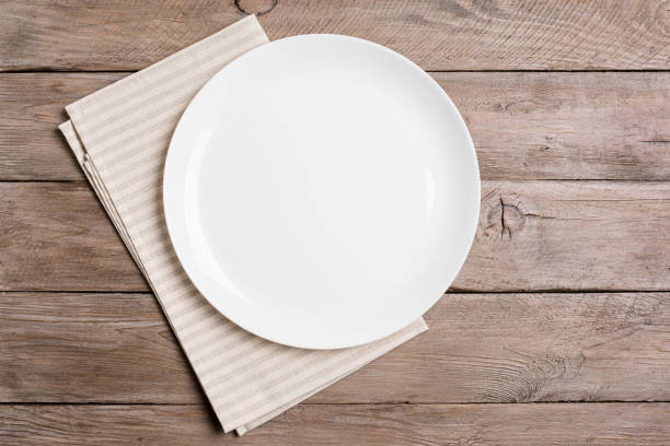istock Empty white plate and napkin on wooden table 2187314576