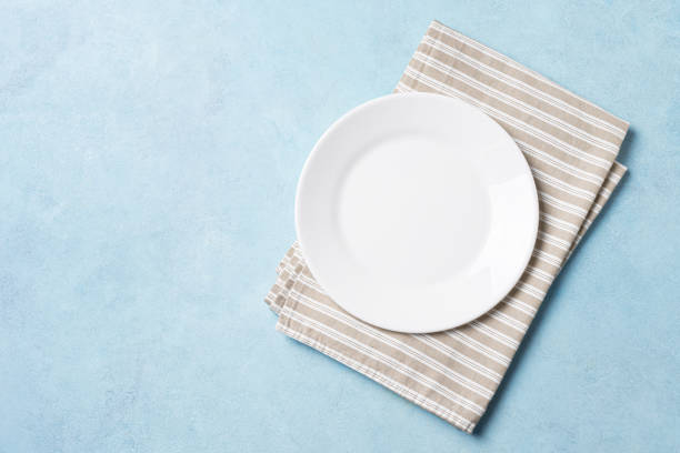istock Empty white plate and napkin on blue background 2187314591