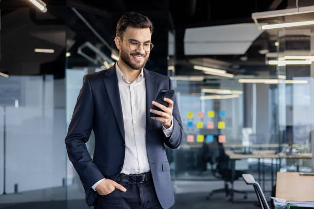 istock Smiling businessman using smartphone in modern office 2187315738