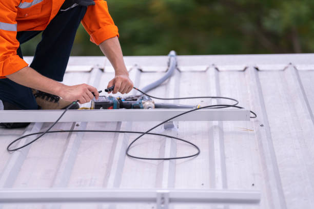 istock Technician in an orange safety uniform and helmet handling an electrical cable on a rooftop. Represents safety, professionalism, and expertise in renewable energy installations and maintenance work. 2187317470