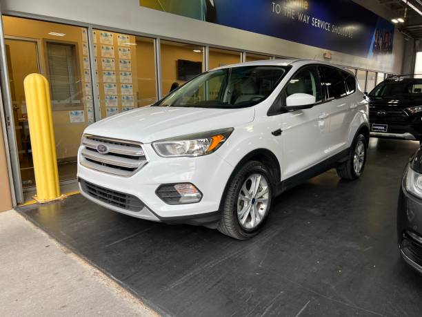 Ford Escape in Service Center A white Ford Escape parked in a service center ready for maintenance and repair just outside a dealership. empty dealership interior stock pictures, royalty-free photos & images
