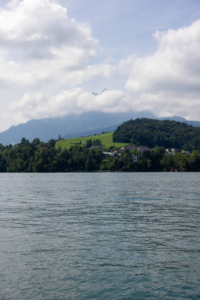 A blue lake with a vibrant green bank with mountains in the background