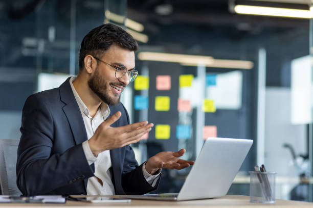 istock Professional man in business suit engaged in virtual meeting in modern office, gesturing while using laptop for communication 2187318191