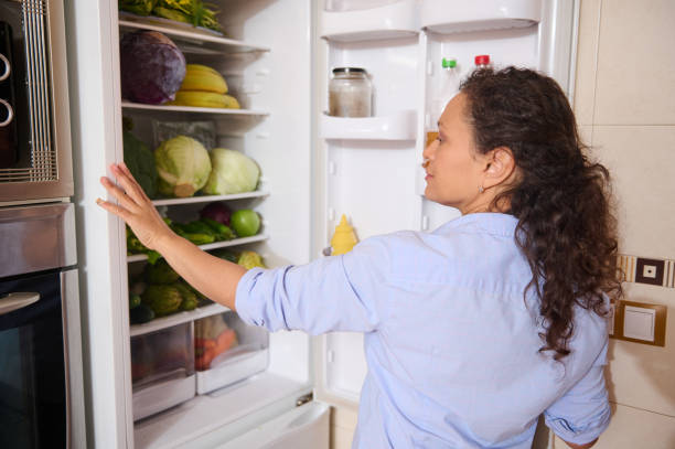 istock Woman looking inside refrigerator filled with fresh vegetables 2187327751