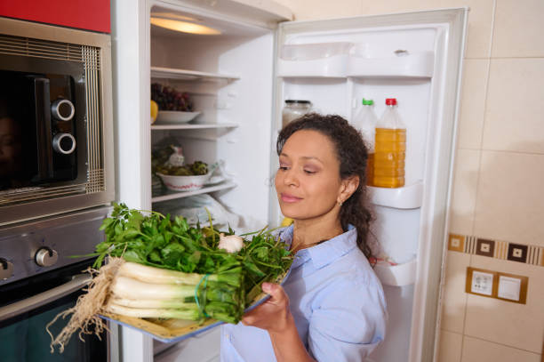 istock Woman holding fresh vegetables in kitchen near open fridge 2187327753