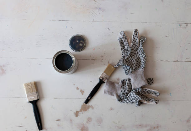 Top view of white table renovation with brushes, paint and protection gloves. DIY home project. Restoring furniture. Flat lay