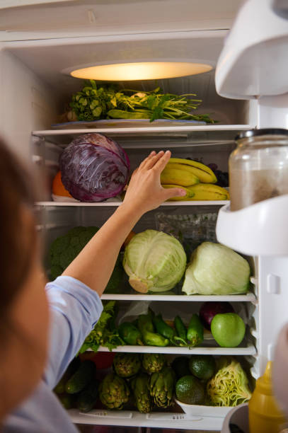 istock Person reaching inside a well-stocked refrigerator with fresh produce 2187328330