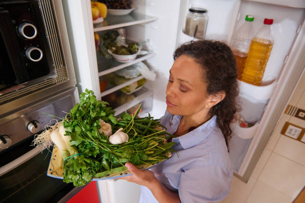 istock Woman holding fresh vegetables in kitchen by open refrigerator 2187328336
