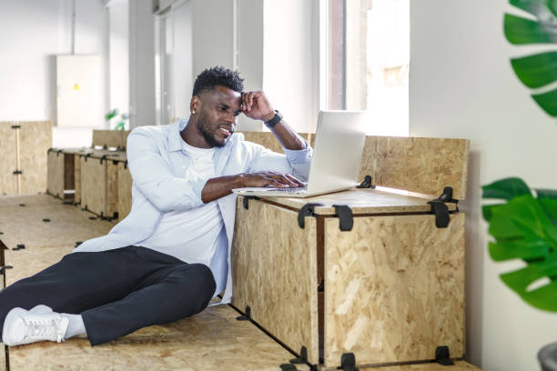 istock Man working on a laptop while sitting on wooden boxes in a modern coworking space 2187338853
