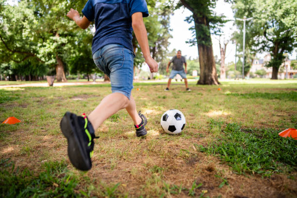 istock Child boy playing soccer with father on the public park 2187338868