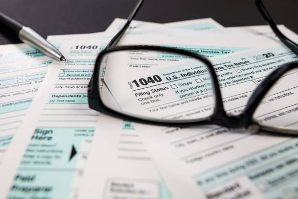 istock tax form 1040 is visible through glasses. financial document. 2187338934